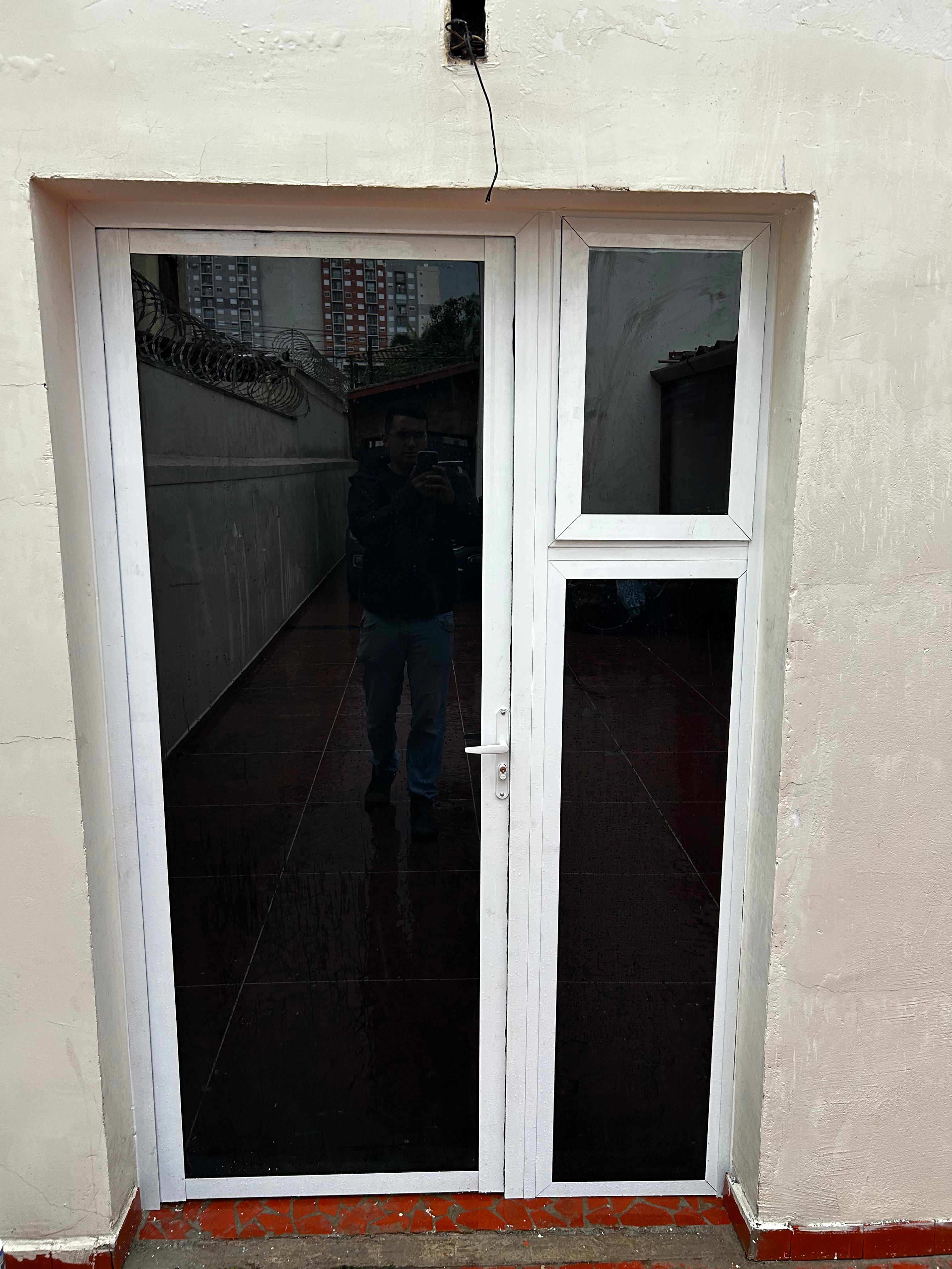 Porta acústica de vidro com estrutura branca instalada sob medida.